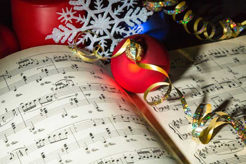 Sheet music with holiday ribbons, balls and a snowflake ornament.