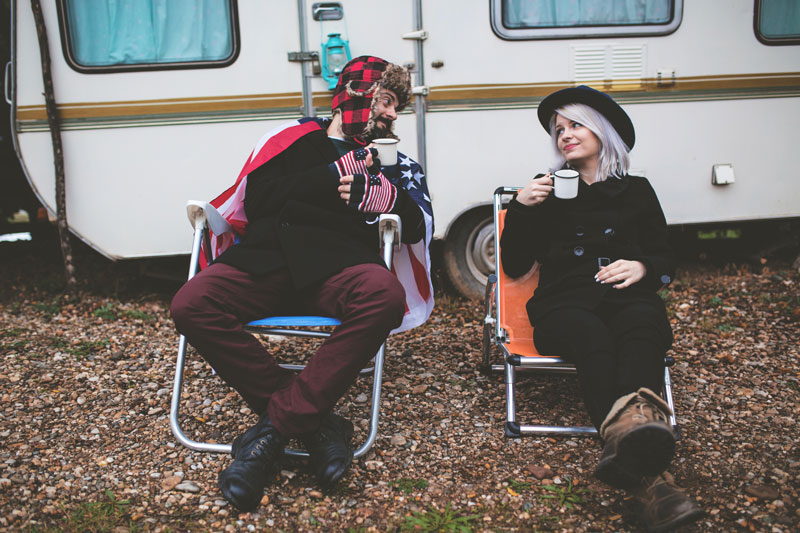 Hip Couple drinking coffee in front of an RV.